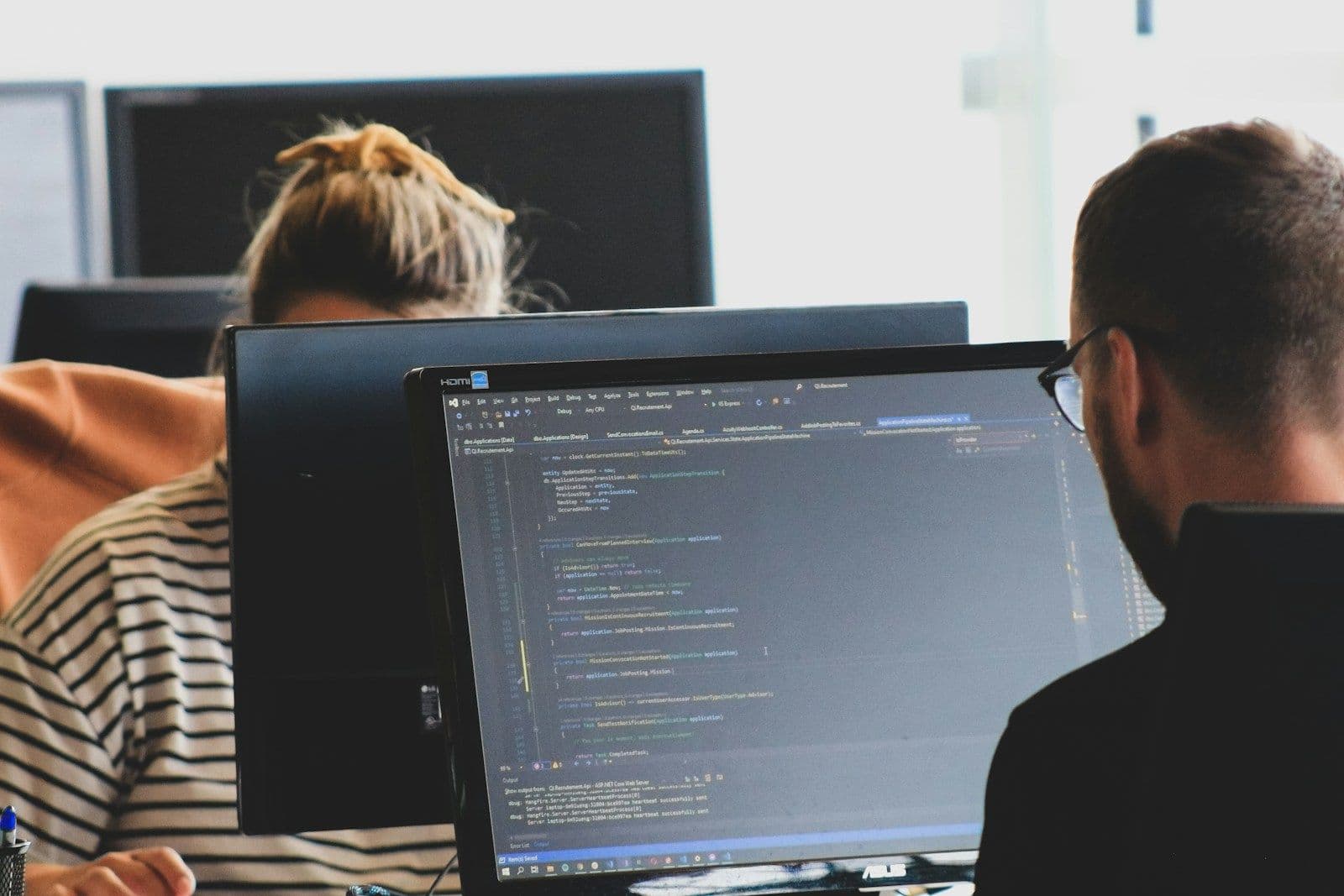 Two developers working side by side at their monitors